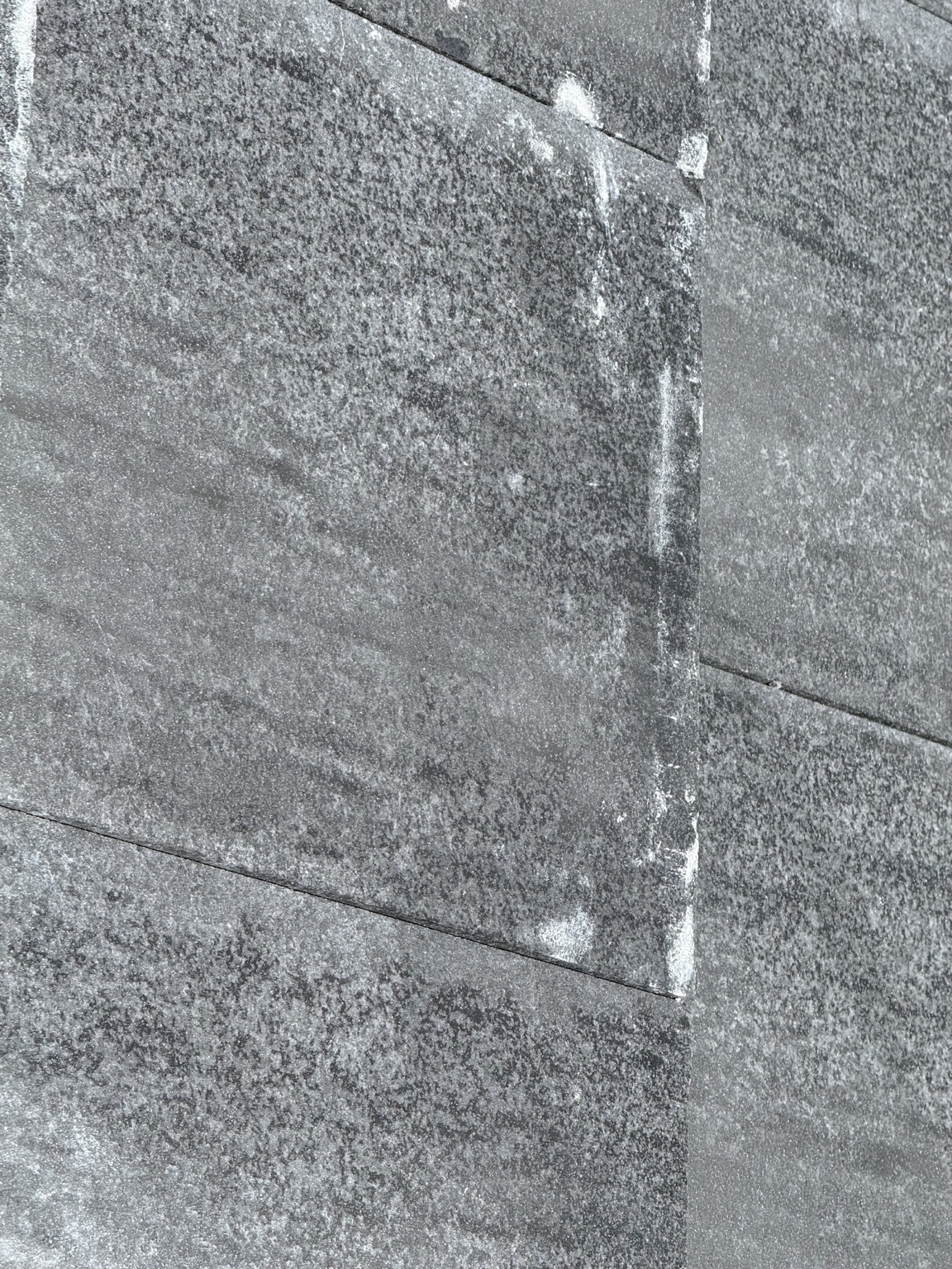 Close-up of the installed dark concrete roof showing white marks and mottled gray areas