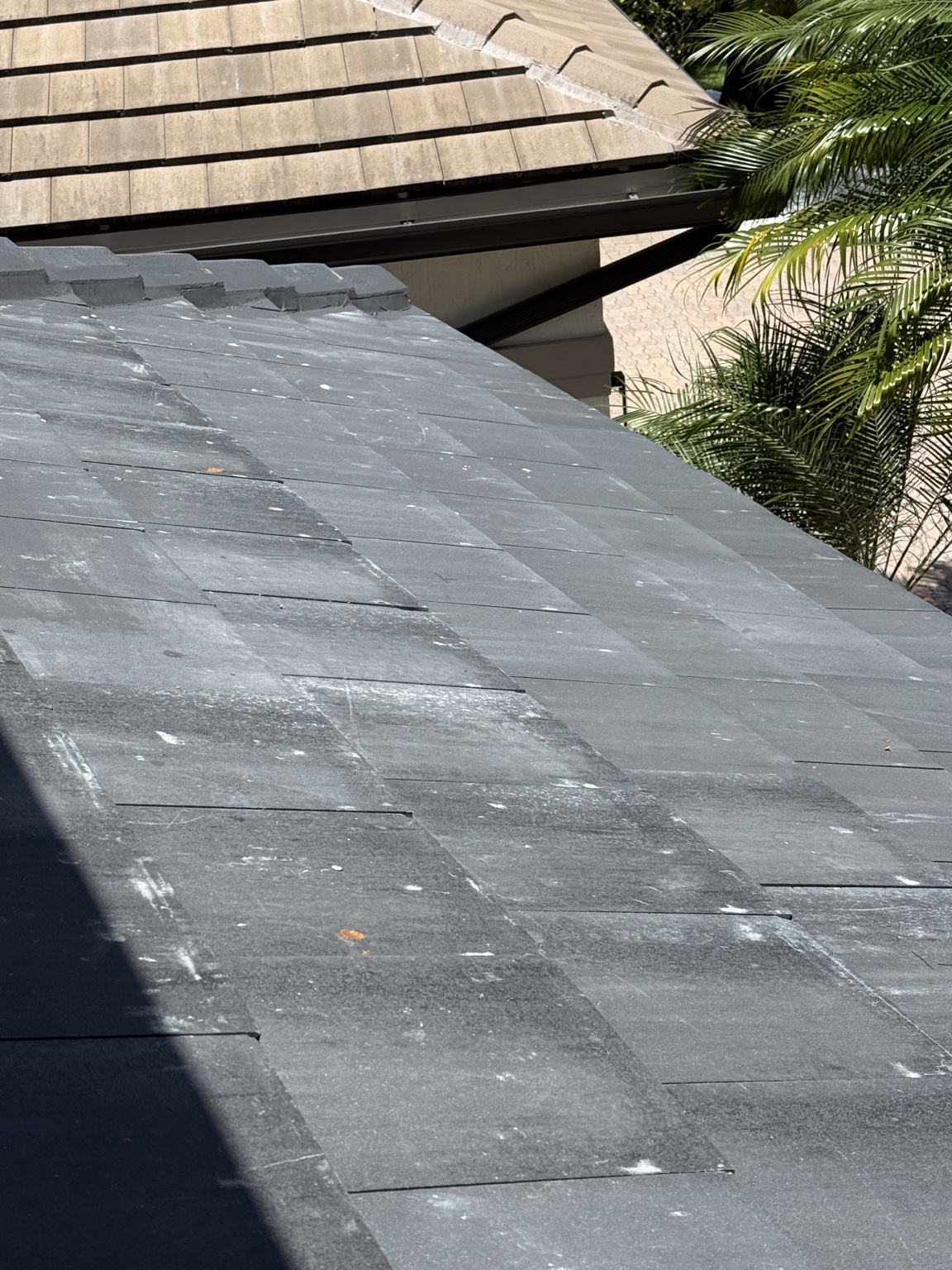 Roof slope showing scattered white marks, pale streaks and uneven gray surface appearance